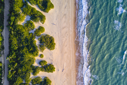 View from above, stunning aerial view of a beautiful and uncontaminated wild beach bathed by a rough sea during the sunset.