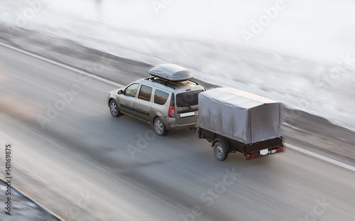 Car with trailer rides on the winter road photo