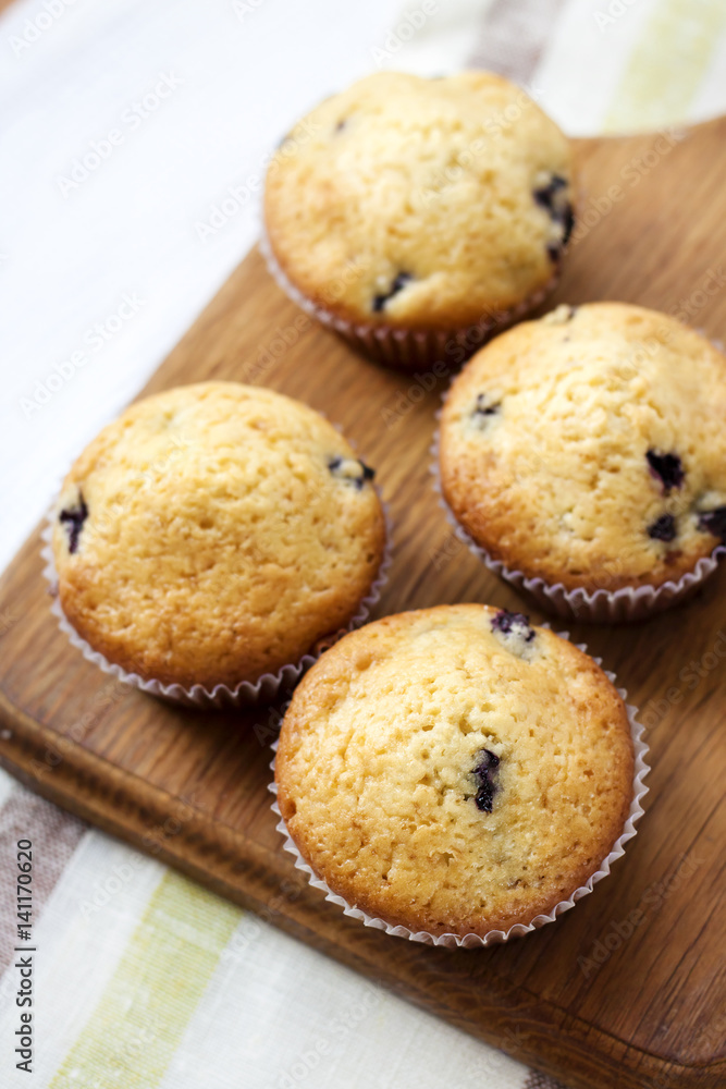 Homemade muffins with blueberries on a wooden board