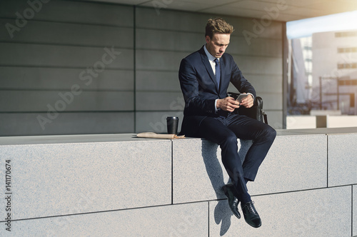Confident stylish businnessman sitting with his phone