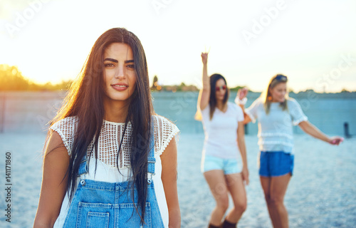 Calm adult woman on beach with dancing friends