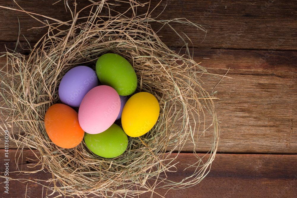 Fototapeta premium Easter eggs in nest on old wooden background