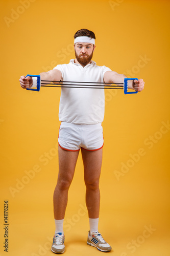 Young athletic man exercising with chest expander or resistance band photo