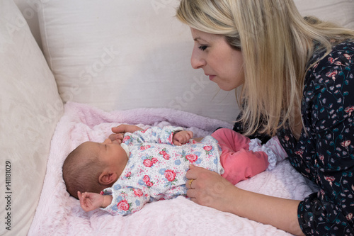 mutter beugt sich über ihr baby auf einer decke