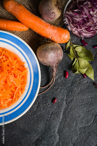 Beets, carrots and cabbage during cooking. Composition on a dark background. Place for text. photo