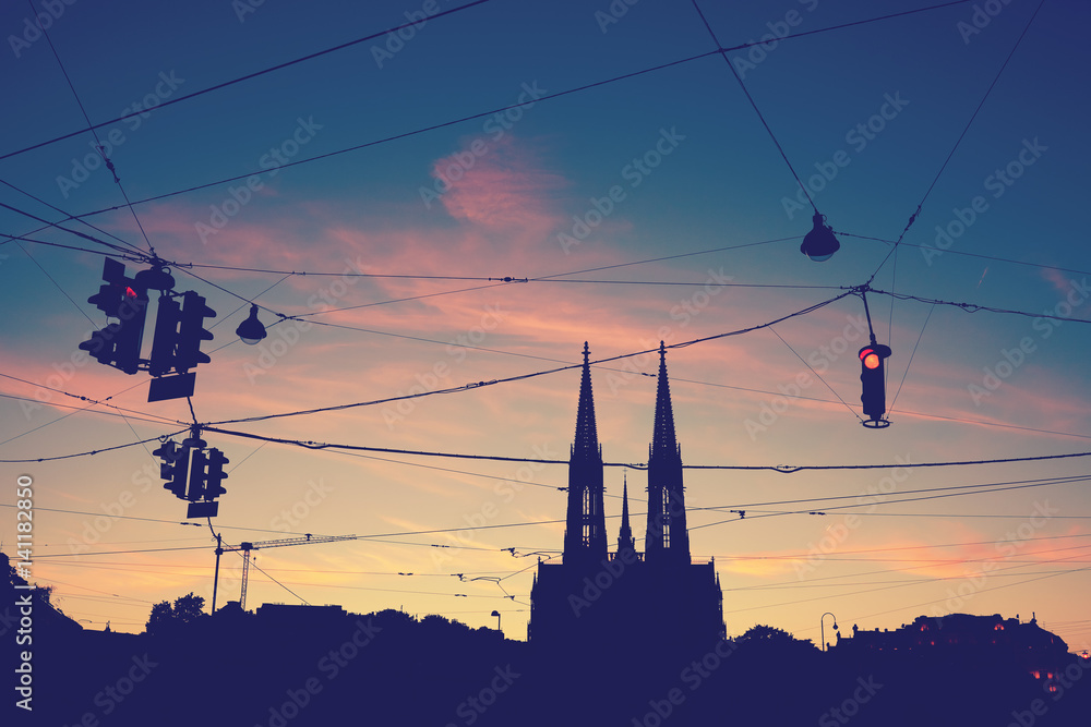 Fototapeta premium Silhouette of the Votive Church (Votivkirche) and suspended stoplights at dusk, color toning applied.