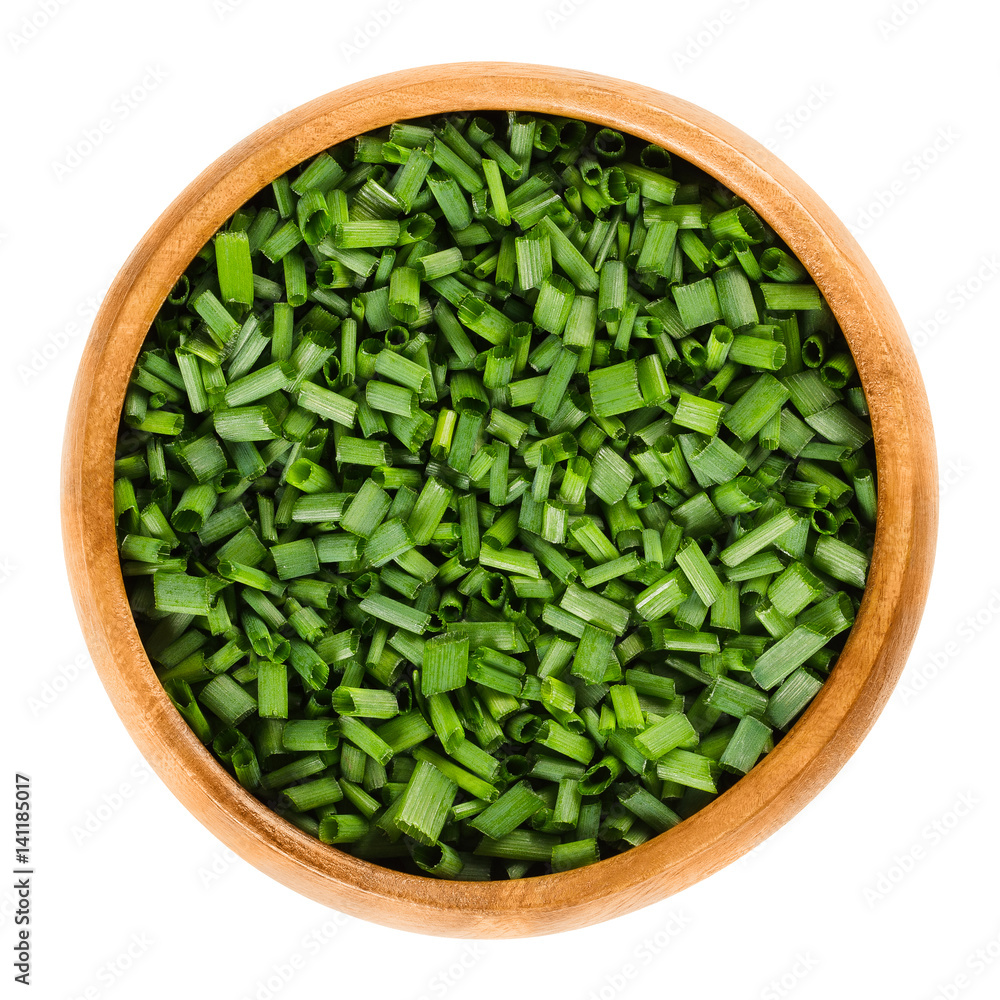 Chopped chives in wooden bowl. Fresh green edible herb of Allium schoenoprasum, used as an ingredient for fish, potatoes and soups. Isolated macro food photo close up from above on white background. - obrazy, fototapety, plakaty 