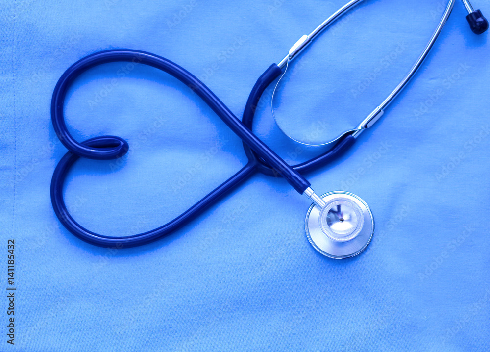 Medical stethoscope twisted in heart shape lying on patient medical history list and blue doctor uniform closeup. Medical help or insurance concept. Cardiology care, health, protection and prevention Medical stethoscope twisted in heart shape lying on patient medical history list and blue doctor uniform closeup. Medical help or insurance concept. Cardiology care, health, protection and prevention