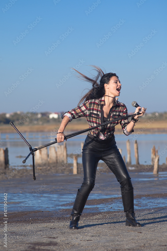 Naklejka premium Rock musician woman singing near water outside