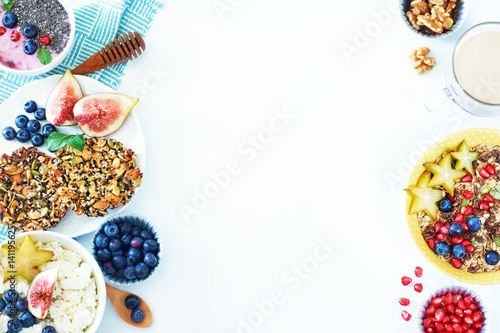 Top view of healthy breakfast food frame over white background with a place for text. Muesli and cottage cheese with blueberry and starfruit, yoghurt with chia, multi-grain cookie and coffee. 