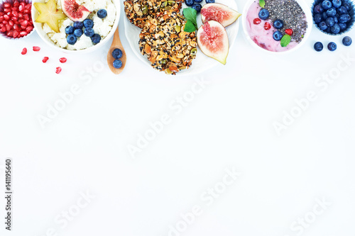 Top view of healthy breakfast with copy space on a white table. Wholegrain cookies, yoghurt with chia seeds, cottage cheese with starfruit and blueberry. 