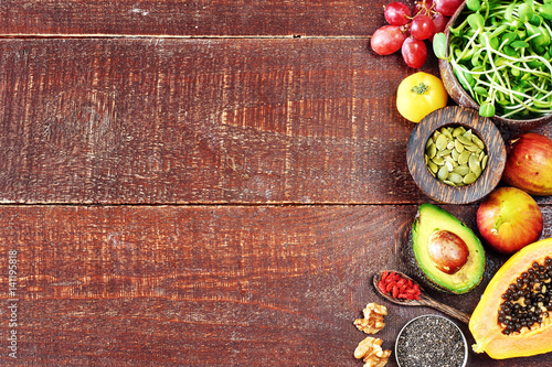 Top view of fresh vegetables, fruits, superfoods, nuts and seeds. Wooden texture background with copy space.