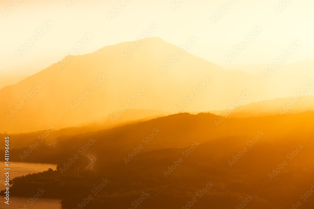 A Winding Highway Road Disappears into Mountain Layers and a Golden Sunset