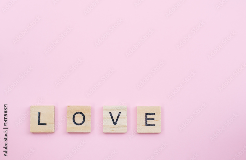 Text wooden blocks spelling the word love on pink background Text wooden blocks spelling the word love on pink background