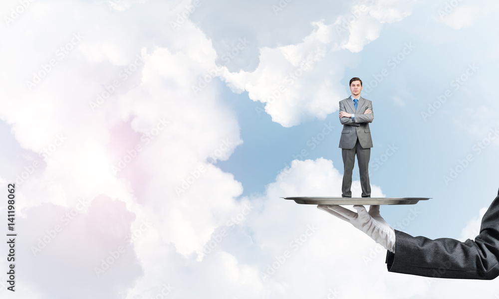 Confident businessman presented on metal tray against blue sky background Confident businessman presented on metal tray against blue sky background