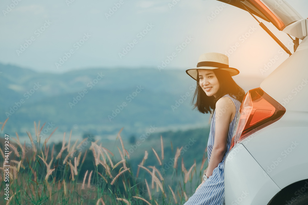 Naklejka premium Woman traveler sitting on hatchback car with mountain background in vintage tone