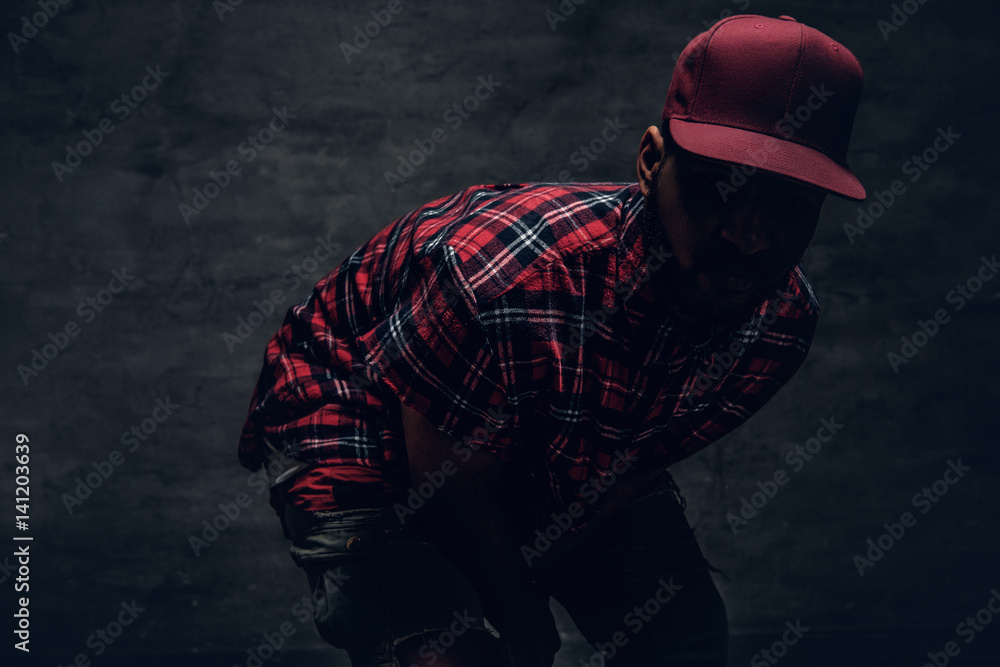 A man dressed in a red fleece shirt and a cap in a shadow. - obrazy, fototapety, plakaty 
