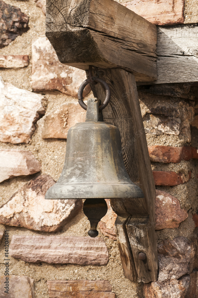 Obraz premium Small church bell closeup on old stone wall background