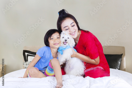 Mother and daughter with dog in bedroom