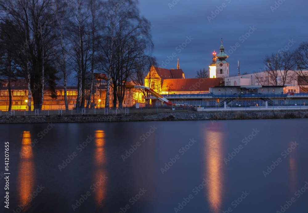Black and white tower in Ceske Budejovice with river, night scene.