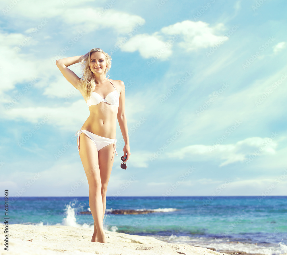 Gorgeous and beautiful girl in white bikini posing on a beach at summer. Sea and sky background. Holiday, resort, concept. Gorgeous and beautiful girl in white bikini posing on a beach at summer. Sea and sky background. Holiday, resort, concept.