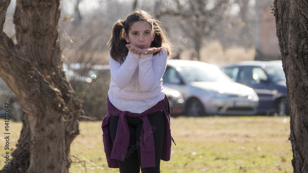 Little girl waving in park during the sunny spring day