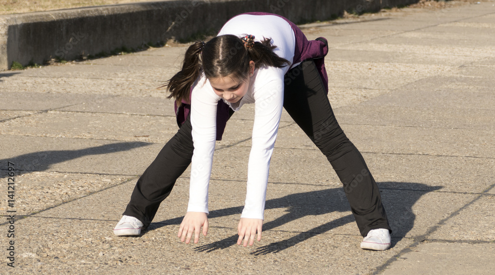 Fototapeta premium Little girl doing exercises in park