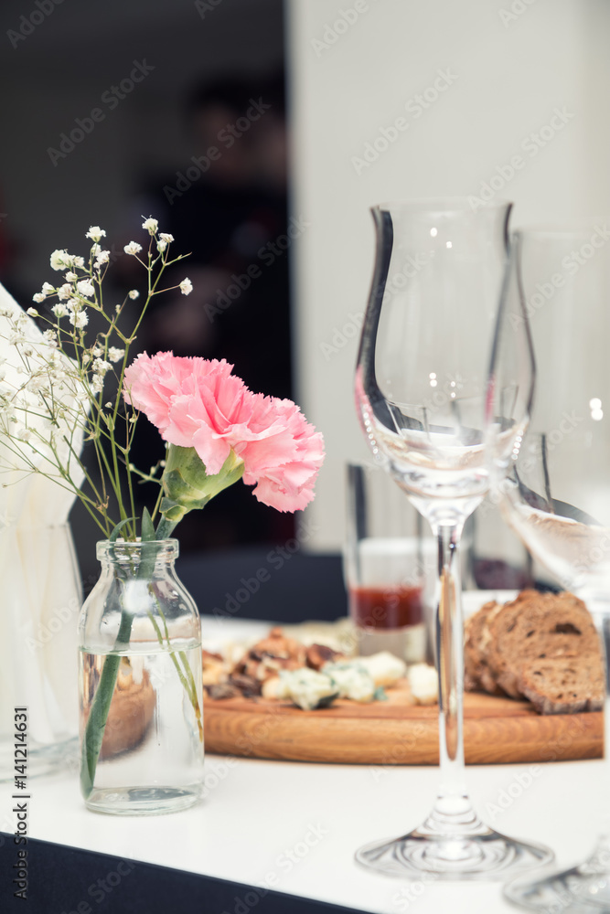Close up picture of wine glasses with flower and empty glasses in restaurant. Serving table prepared for event party or wedding. Soft focus, selective focus. Toned. Close up picture of wine glasses with flower and empty glasses in restaurant. Serving table prepared for event party or wedding. Soft focus, selective focus. Toned.