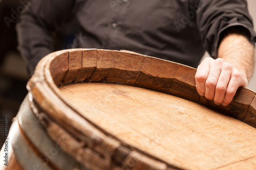 Man standing with his hand on an oak barrel photo