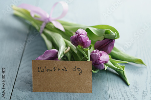tulips on blue wood background with valentines day paper card, shallow focus