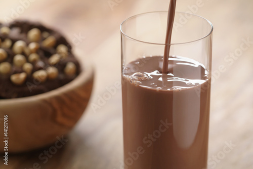Canvas Print pouring chocolate milk in glass with homemade chocolate cookies with hazelnuts o