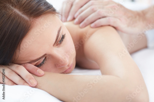 Beautiful young woman lying while massage therapist massaging her shoulders.  Health  beauty  resort and relaxation concept.