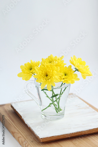 Wallpaper Mural bouquet of yellow Chrysanthemum flowers in glass on table, abstract light background. floral gift. festive composition with flowers. template for design Torontodigital.ca