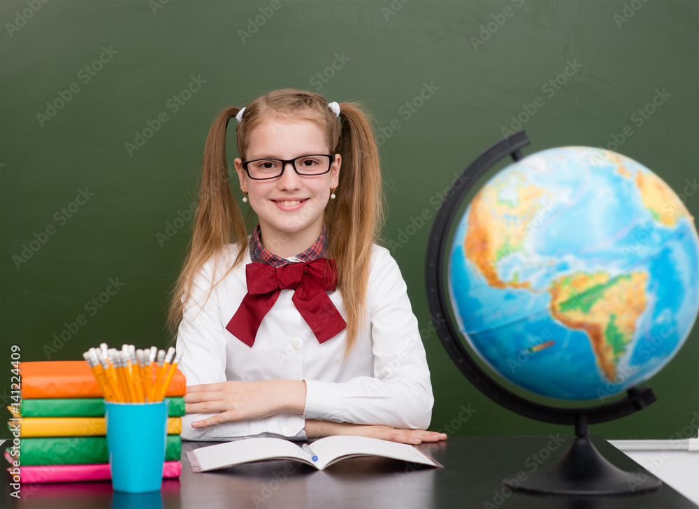 Schoolgirl sitting in classroom near empty green chalkboard Schoolgirl sitting in classroom near empty green chalkboard
