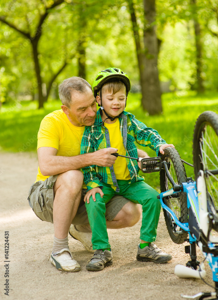 Fototapeta premium Grandson with his grandfather pumped wheel bicycle
