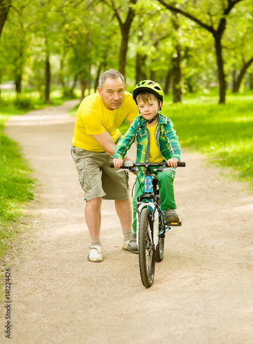 Grandfather teaches his grandson to ride a bike