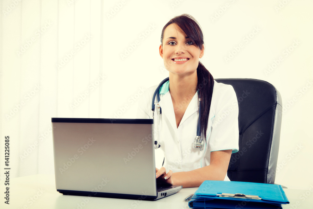 Female doctor sitting at office desk and smiling at camera Female doctor sitting at office desk and smiling at camera