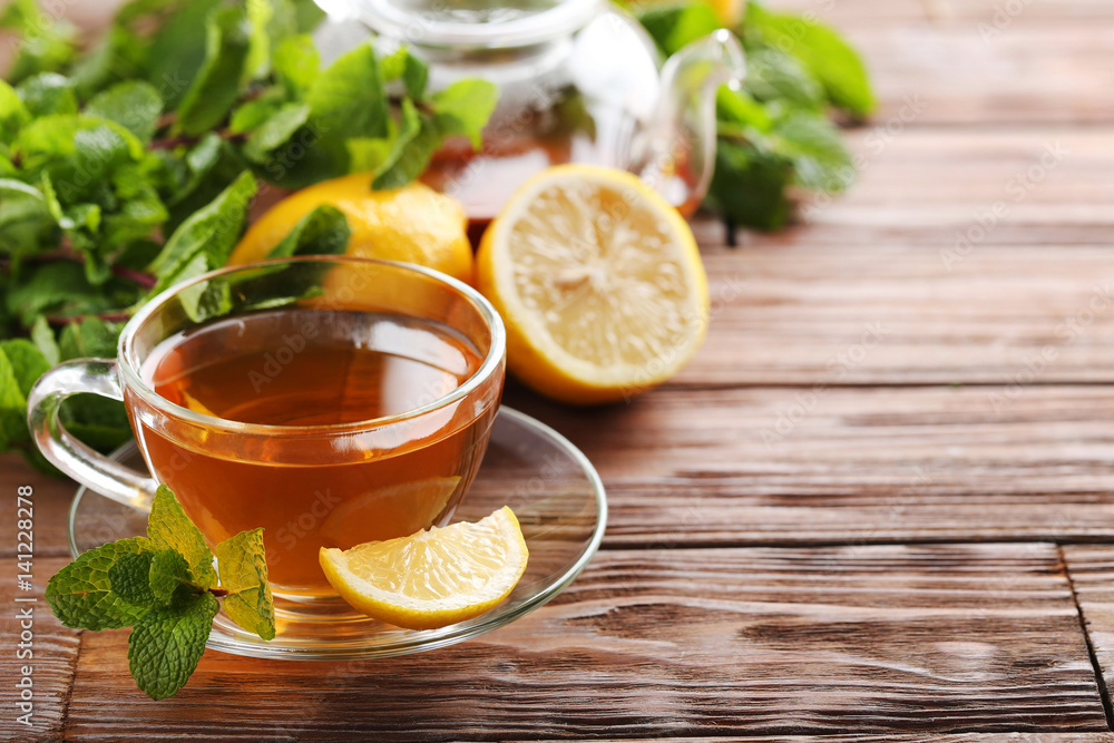 Cup of tea with mint and lemon on brown wooden table Cup of tea with mint and lemon on brown wooden table