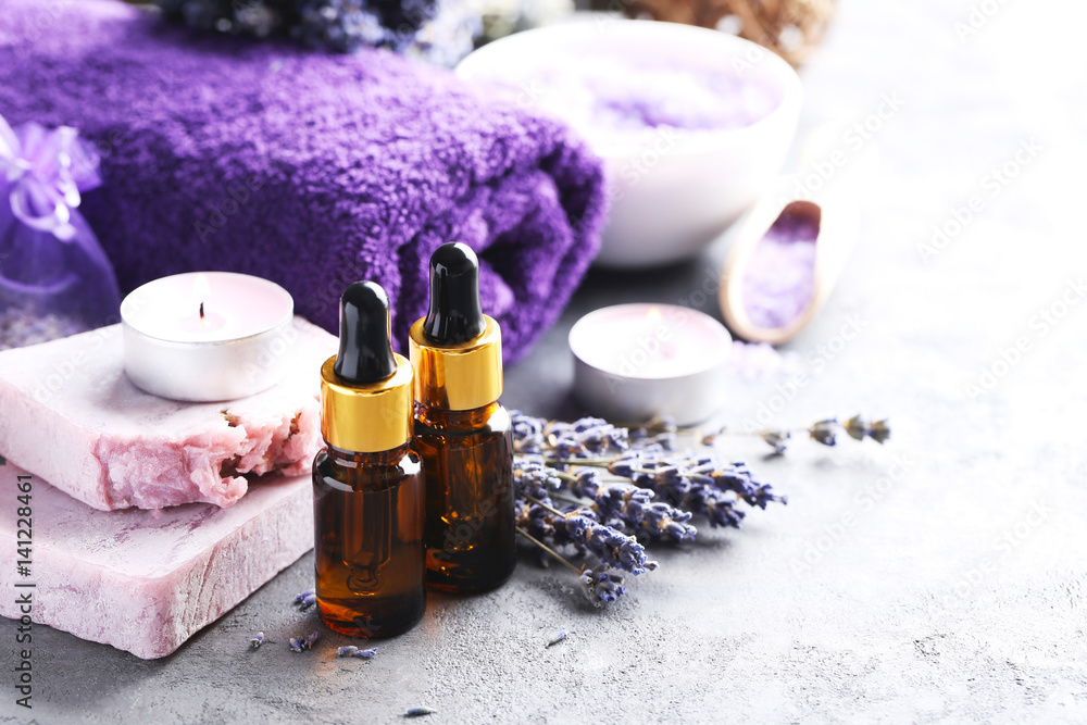 Lavender oil with soap and flowers on grey table Lavender oil with soap and flowers on grey table