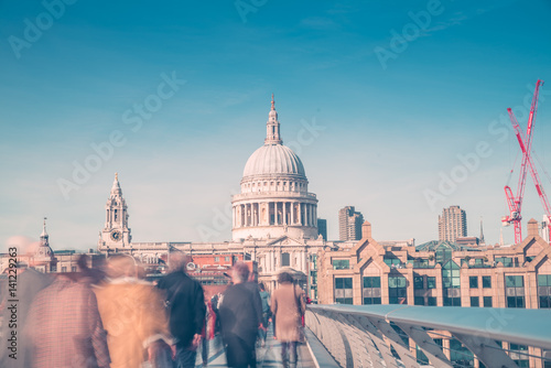 Fototapeta Naklejka Na Ścianę i Meble -  Unrecognizable people  walking over Millennium Bridge on a sunny spring day in London,UK. St Paul Cathedral in the background.