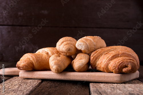 Croissants on board on wooden background. Rustic style.