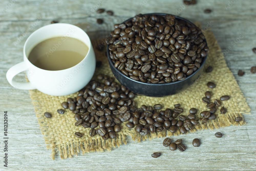 Coffee cup with coffee beans placed on the table,.On dark wood Coffee cup with coffee beans placed on the table,.On dark wood