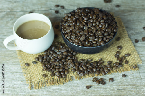 Coffee cup with coffee beans placed on the table,.On dark wood