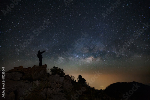 A Man is standing next to the milky way galaxy pointing on a bright star on Doi Luang Chiang Dao mountain, Long exposure photograph, with grain