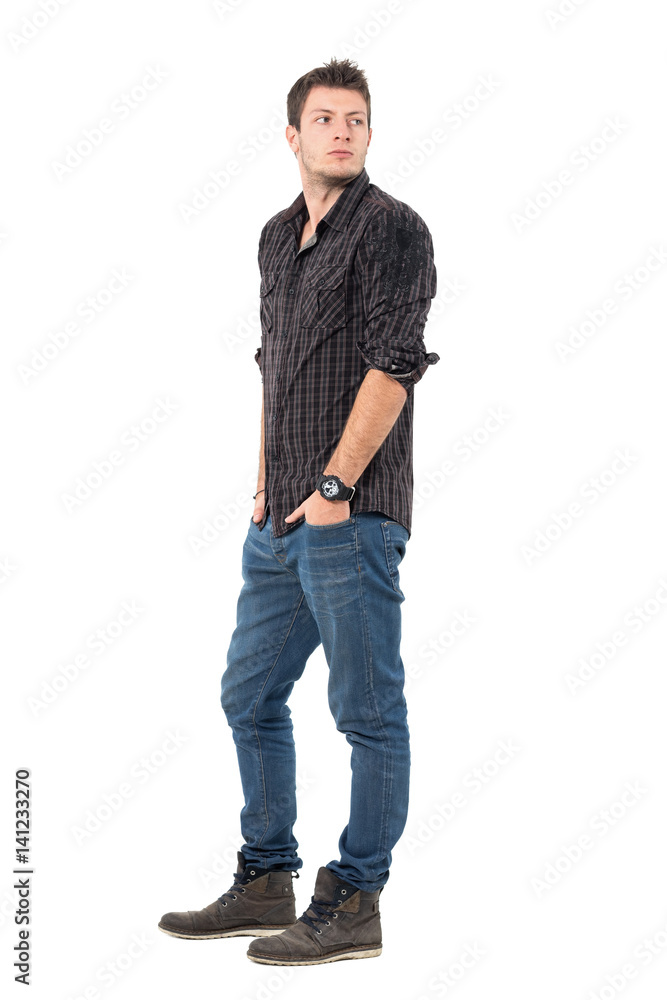 Handsome young man in dark grayish plaid shirt looking back over shoulder. Full body length portrait isolated over white studio background. Handsome young man in dark grayish plaid shirt looking back over shoulder. Full body length portrait isolated over white studio background.