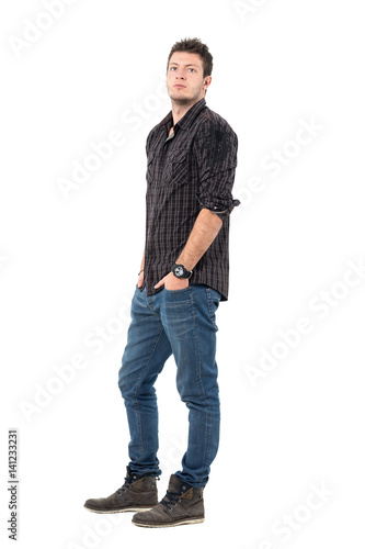 Serious confident young casual man in jeans and shirt looking at camera. Full body length portrait isolated over white studio background. 