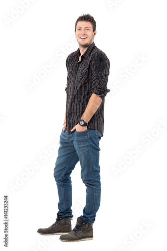 Relaxed happy laughing young man wearing jeans and plaid shirt. Full body length portrait isolated over white studio background. 