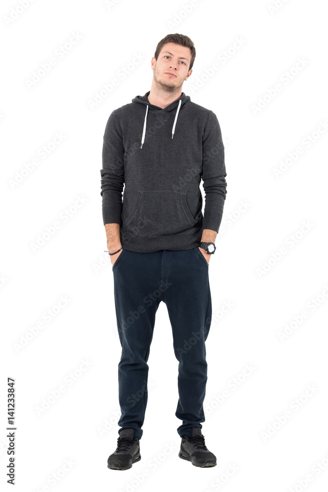 Relaxed young sporty man in hooded sweatshirt and sweatpants looking at camera. Full body length portrait over white studio background. Relaxed young sporty man in hooded sweatshirt and sweatpants looking at camera. Full body length portrait over white studio background.