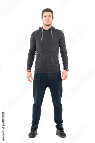 Happy young man in comfortable casual sportswear smiling and looking at camera. Full body length portrait over white studio background.