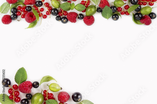 Fototapeta Naklejka Na Ścianę i Meble -  Various fresh summer berries on white background. Ripe raspberries, currants, gooseberries, mint and basil leaves. Berries at border of image with copy space for text. Background berries.